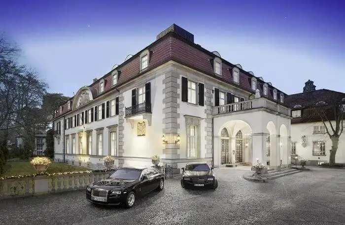 A luxury mansion in Berlin with two cars parked in front of it.