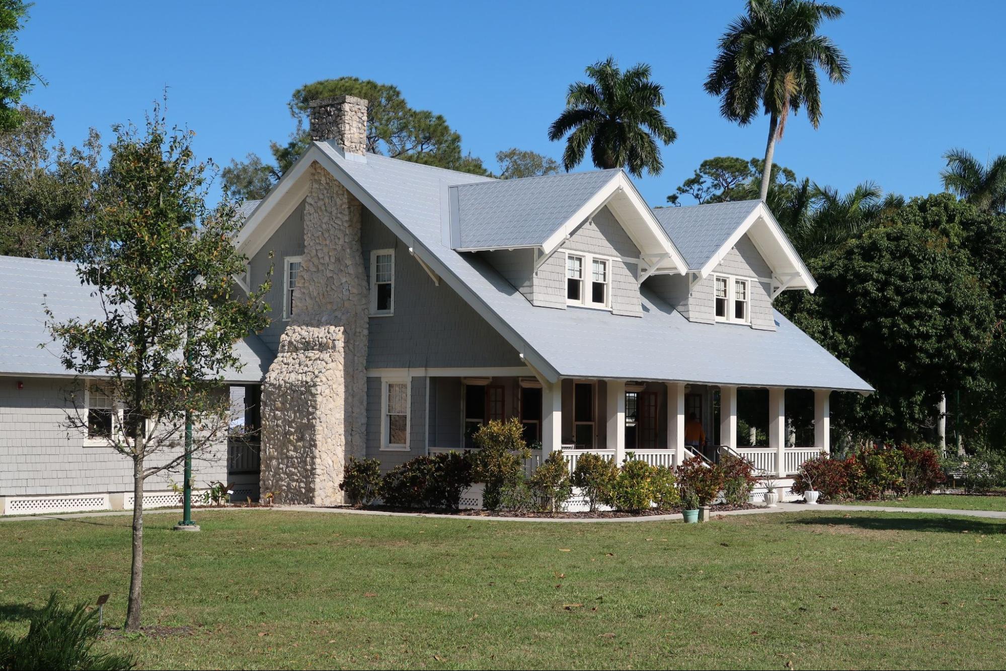 A white house with a gray roof and palm trees.