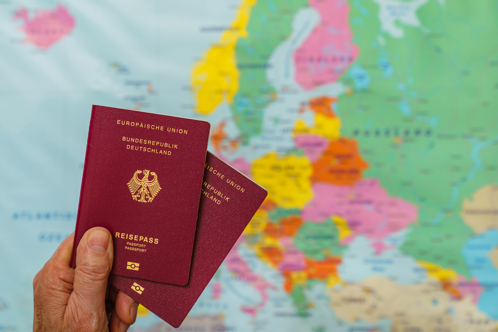 A man holding two passports in front of a Golden Visa Europe map.