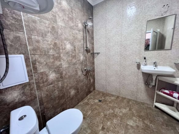 Bathroom with beige and brown tiles, shower, toilet, and sink in Magnolia Residence 5.